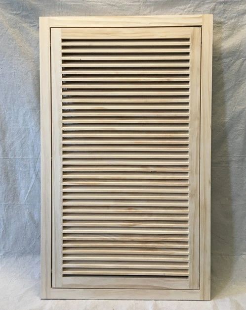 A wooden cabinet with a louvered door.