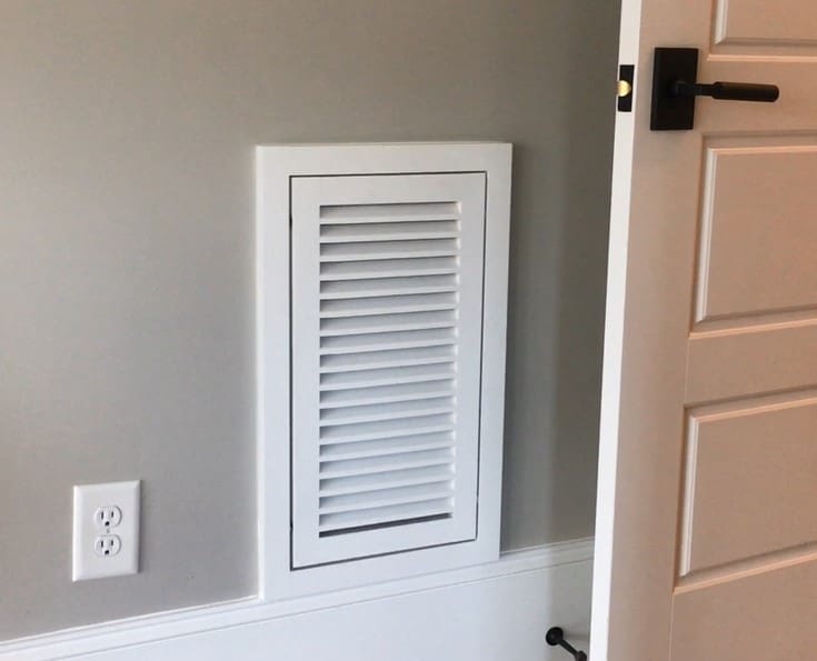 A white door and window frame with a vent on the wall.