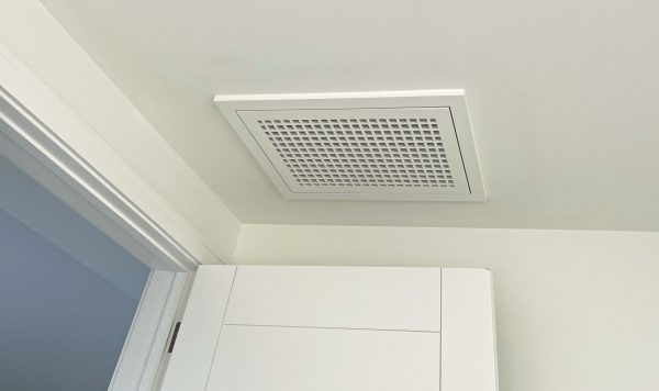 Wood Return Egg Crate Filter Grille mounted on a ceiling near an open door.